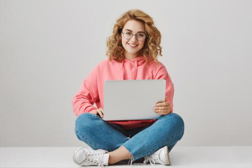 cute-freelance-girl-using-laptop-sitting-floor-smiling